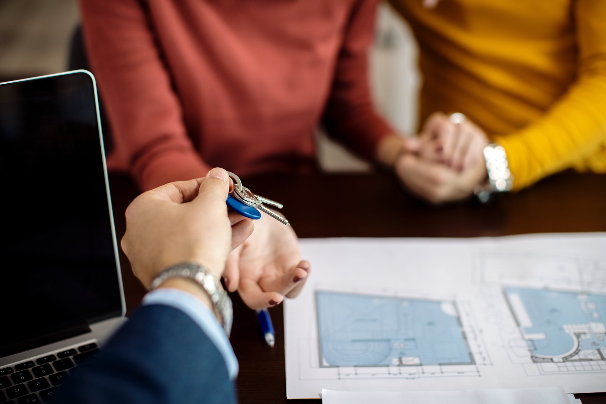 closeup-real-estate-agent-giving-couple-keys-their-new-home