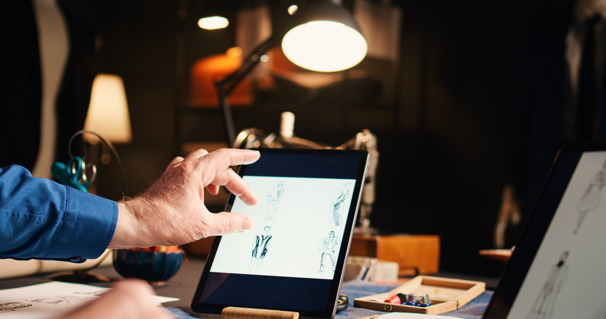 old-couturier-checking-fashion-sketches-atelier-working-modern-designs-with-laptop-tablet-experienced-designer-searching-handmade-models-online-needlework-handheld-shot